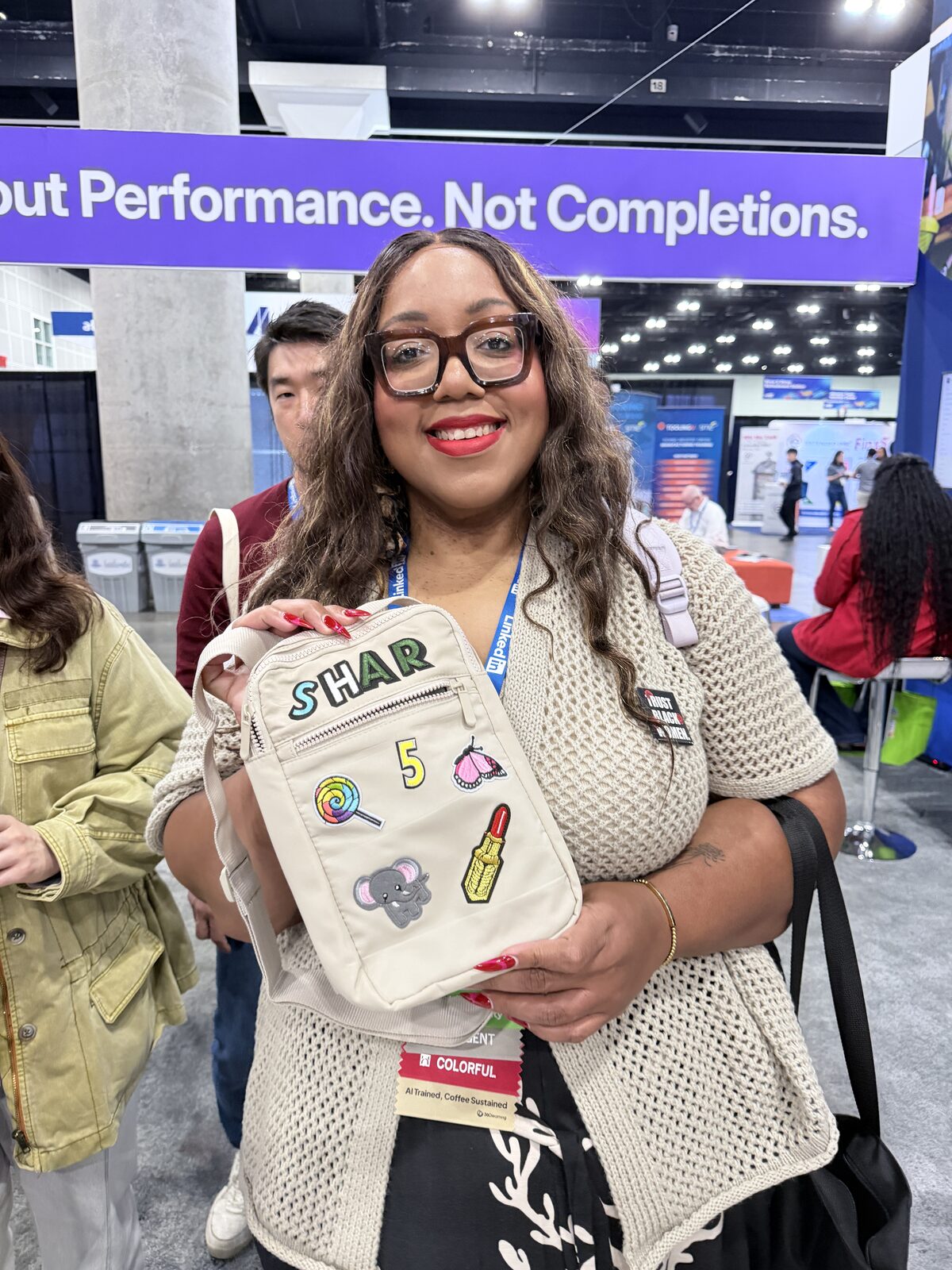 Attendee holding a crossbody bag with chenille letters spelling Shar plus a five, lollipop, butterfly, and lipstick patches