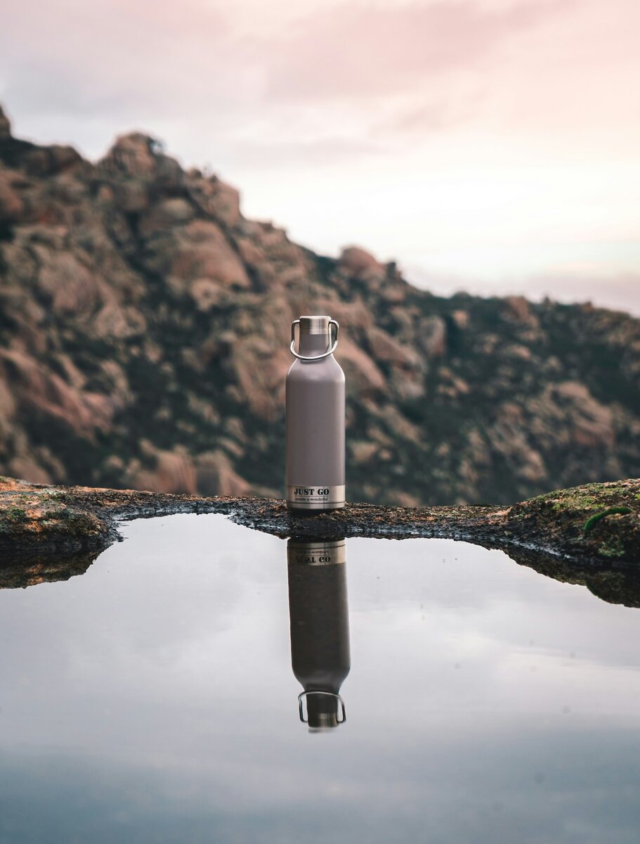 Laser engraved steel water bottle photographed outdoors beside a still pool